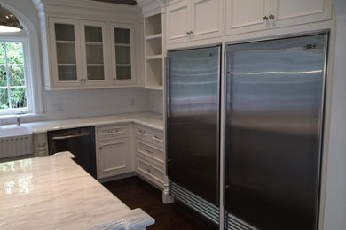 Photo of a large transitional l-shaped eat-in kitchen in Los Angeles with a farmhouse sink, shaker cabinets, white cabinets, marble benchtops, white splashback, subway tile splashback, stainless steel appliances, dark hardwood floors and with island.