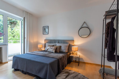 デュッセルドルフにある小さなコンテンポラリースタイルのおしゃれな主寝室 (白い壁、ラミネートの床、暖炉なし、茶色い床) のインテリア