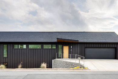 Imagen de fachada de casa marrón y negra contemporánea de dos plantas con revestimiento de metal, tejado a dos aguas y tejado de teja de madera