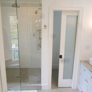 Inspiration for a large victorian beige tile and ceramic tile ceramic floor alcove shower remodel in New York with flat-panel cabinets, white cabinets, a two-piece toilet, beige walls, a vessel sink and solid surface countertops