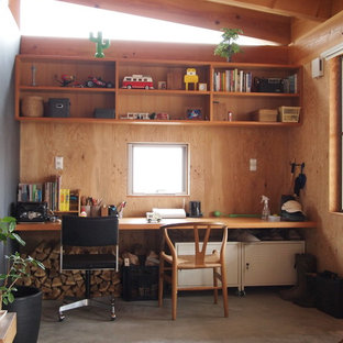 他の地域の小さいアジアンスタイルのおしゃれなホームオフィス・仕事部屋 (コンクリートの床、茶色い壁、造り付け机) の写真