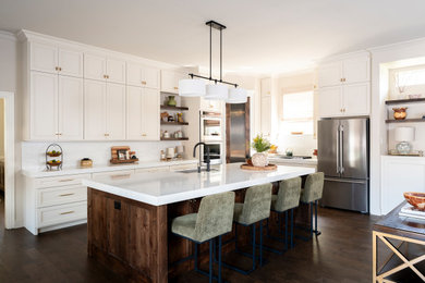 Example of a mid-sized transitional dark wood floor and brown floor eat-in kitchen design in Dallas with a drop-in sink, shaker cabinets, white cabinets, quartzite countertops, white backsplash, quartz backsplash, stainless steel appliances, an island and white countertops