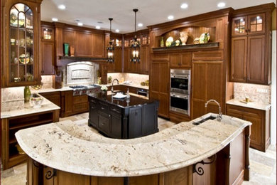 Inspiration for a mid-sized timeless l-shaped ceramic tile enclosed kitchen remodel in New York with an undermount sink, raised-panel cabinets, medium tone wood cabinets, marble countertops, beige backsplash, ceramic backsplash, stainless steel appliances and two islands