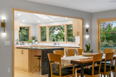 Inspiration for a midcentury u-shaped kitchen in Minneapolis with flat-panel cabinets, light wood cabinets, engineered stone countertops, white splashback, engineered quartz splashback, integrated appliances, light hardwood flooring, an island, grey worktops and a vaulted ceiling.