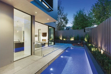 Photo of a mid-sized modern backyard rectangular lap pool in Melbourne with natural stone pavers.