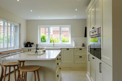 Large traditional grey and white single-wall open plan kitchen in Other with a belfast sink, beaded cabinets, medium wood cabinets, quartz worktops, white splashback, engineered quartz splashback, black appliances, porcelain flooring, an island, grey floors, white worktops and feature lighting.