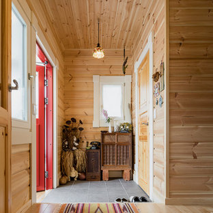 他の地域の片開きドア北欧スタイルのおしゃれな玄関 (茶色い壁、赤いドア、グレーの床) の写真