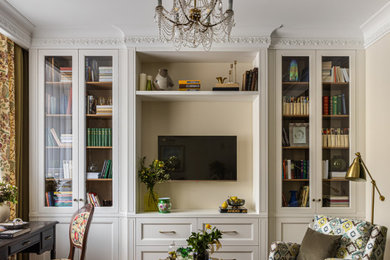 Diseño de biblioteca en casa abierta clásica de tamaño medio con paredes amarillas, suelo de madera en tonos medios, televisor colgado en la pared y suelo beige