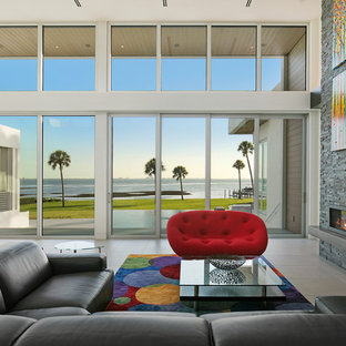 Inspiration för stora moderna allrum med öppen planlösning, med vita väggar, klinkergolv i porslin, en bred öppen spis, en spiselkrans i sten, grått golv och en väggmonterad TV