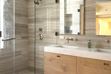 Mid-sized trendy master gray tile and marble tile marble floor, gray floor and double-sink bathroom photo in New York with flat-panel cabinets, brown cabinets, a one-piece toilet, gray walls, an integrated sink, marble countertops, a hinged shower door, white countertops and a floating vanity