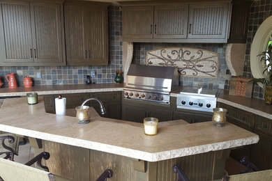Inspiration for a large mediterranean l-shaped limestone floor eat-in kitchen remodel in Charlotte with a single-bowl sink, beaded inset cabinets, distressed cabinets, gray backsplash, stone tile backsplash, stainless steel appliances, an island and limestone countertops