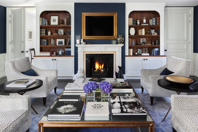 This is an example of a large traditional formal enclosed living room in London with blue walls, dark hardwood floors, a standard fireplace, a stone fireplace surround and a concealed tv.