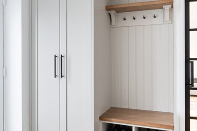 Photo of a medium sized contemporary galley utility room in Hertfordshire with shaker cabinets, grey cabinets, quartz worktops, white walls, light hardwood flooring, a stacked washer and dryer, beige floors and white worktops.