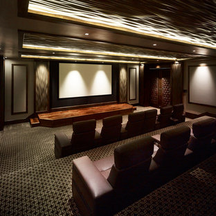 Cette photo montre une très grande salle de cinéma chic fermée avec un mur marron, moquette, un écran de projection et un sol multicolore.