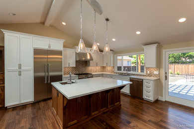 Mid-sized elegant medium tone wood floor, brown floor and exposed beam eat-in kitchen photo in San Francisco with a drop-in sink, shaker cabinets, white cabinets, quartz countertops, beige backsplash, ceramic backsplash, stainless steel appliances, an island and white countertops