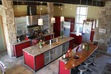 Open concept kitchen - large contemporary u-shaped concrete floor open concept kitchen idea in Austin with a single-bowl sink, louvered cabinets, red cabinets, granite countertops, beige backsplash, stone slab backsplash, stainless steel appliances and two islands