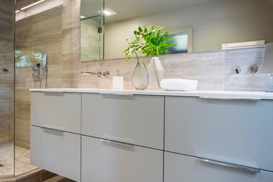 Inspiration for a modern master bathroom in Cincinnati with flat-panel cabinets, grey cabinets, a corner shower, a wall-mount toilet, gray tile, an undermount sink, grey floor, a hinged shower door and white benchtops.