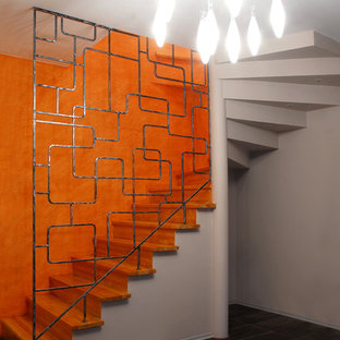 Modelo de escalera en L, contemporánea, con escalones de madera, contrahuellas de madera y barandilla de metal