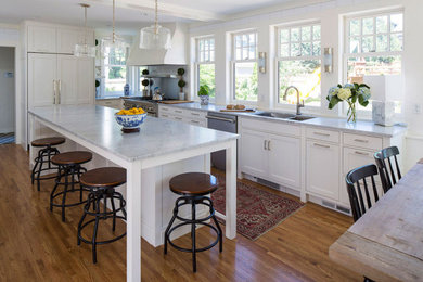 Example of a cottage u-shaped medium tone wood floor eat-in kitchen design in Minneapolis with an undermount sink, recessed-panel cabinets, white cabinets, marble countertops, metallic backsplash, stainless steel appliances, an island and white countertops