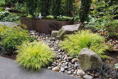 This is an example of a contemporary shade front yard gravel and metal fence water fountain landscape in Seattle for spring.