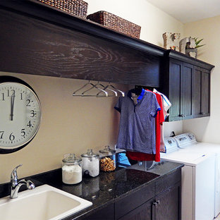 Inspiration for a large modern single-wall separated utility room in Tampa with a built-in sink, recessed-panel cabinets, dark wood cabinets, onyx worktops, beige walls, porcelain flooring and a side by side washer and dryer.