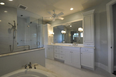 Example of a minimalist master glass sheet ceramic tile corner bathtub design in Miami with raised-panel cabinets, light wood cabinets and granite countertops