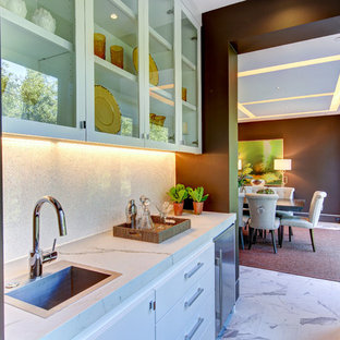 サンフランシスコの巨大なコンテンポラリースタイルのおしゃれなウェットバー (ドロップインシンク、タイルカウンター、白いキッチンパネル、磁器タイルの床、ガラス扉のキャビネット、白いキャビネット、石スラブのキッチンパネル、白いキッチンカウンター) の写真