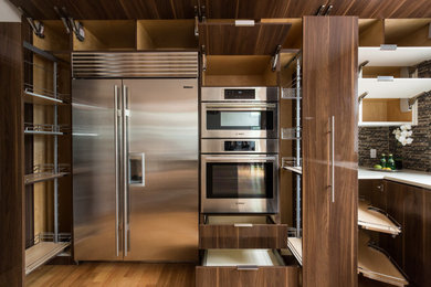 Large contemporary l-shaped kitchen pantry in DC Metro with an undermount sink, flat-panel cabinets, medium wood cabinets, quartz benchtops, brown splashback, mosaic tile splashback, stainless steel appliances, medium hardwood floors, with island, beige floor and beige benchtop.