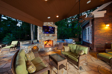 Photo of a large country backyard patio in Charlotte with natural stone pavers, a gazebo/cabana and an outdoor kitchen.