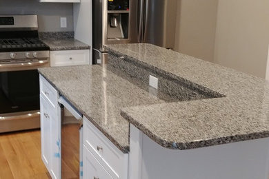 Open concept kitchen - mid-sized traditional l-shaped light wood floor open concept kitchen idea in Boston with shaker cabinets, white cabinets, granite countertops, beige backsplash, stainless steel appliances and an island