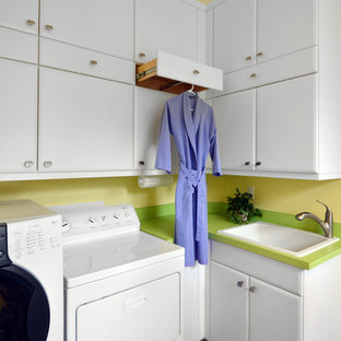 マイアミの中サイズのコンテンポラリースタイルのおしゃれな洗濯室 (ドロップインシンク、レイズドパネル扉のキャビネット、白いキャビネット、磁器タイルの床、左右配置の洗濯機・乾燥機、茶色い床、黄色い壁) の写真