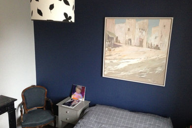 Exemple d'une grande chambre d'amis rétro avec un mur bleu, un sol en bois brun et un sol noir.