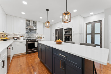 Mid-sized transitional kitchen photo in DC Metro with an undermount sink, shaker cabinets, quartz countertops, marble backsplash, black appliances and an island