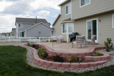 Example of a mid-sized classic backyard stone patio design in Denver with no cover