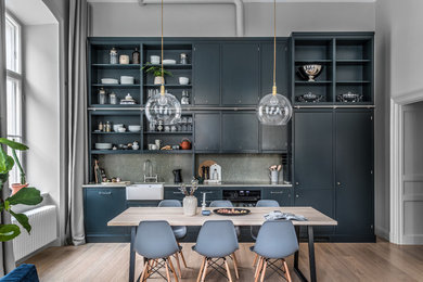 Photo of a contemporary single-wall kitchen in Stockholm with a farmhouse sink, flat-panel cabinets, black cabinets, grey splashback, panelled appliances, dark hardwood floors, no island, brown floor and grey benchtop.