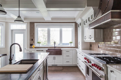 Large elegant u-shaped ceramic tile, brown floor and coffered ceiling open concept kitchen photo in Edmonton with a farmhouse sink, raised-panel cabinets, white cabinets, quartz countertops, beige backsplash, subway tile backsplash, stainless steel appliances, an island and multicolored countertops
