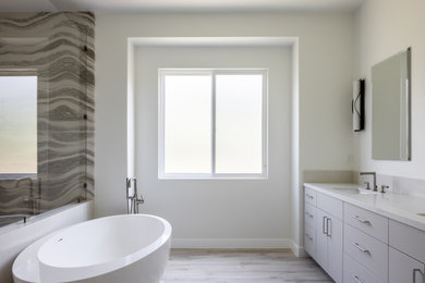 Modern inredning av ett stort vit vitt en-suite badrum, med släta luckor, grå skåp, ett fristående badkar, våtrum, flerfärgad kakel, vita väggar, ljust trägolv, ett undermonterad handfat och dusch med gångjärnsdörr