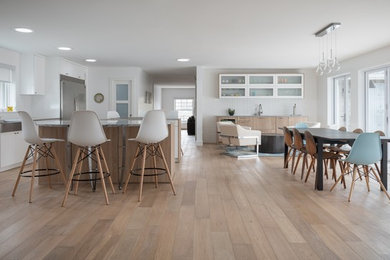 Example of a huge 1960s single-wall light wood floor and brown floor eat-in kitchen design in Denver with a farmhouse sink, flat-panel cabinets, white cabinets, quartzite countertops, white backsplash, porcelain backsplash, stainless steel appliances, two islands and gray countertops