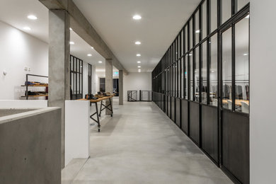 Modelo de despacho minimalista con paredes blancas, suelo de cemento, escritorio independiente y suelo gris