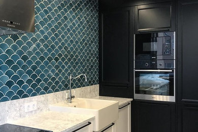 This is an example of a mid-sized scandinavian single-wall separate kitchen in Yekaterinburg with a drop-in sink, recessed-panel cabinets, white cabinets, solid surface benchtops, blue splashback, mosaic tile splashback, black appliances, ceramic floors, no island, multi-coloured floor and grey benchtop.