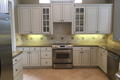 Inspiration for a timeless ceramic tile and beige floor kitchen remodel in Miami with raised-panel cabinets, white cabinets, granite countertops, beige backsplash, marble backsplash and stainless steel appliances