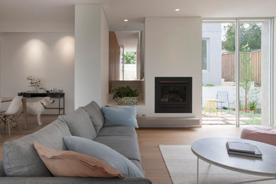 Photo of a large contemporary open concept living room in Sydney with white walls, dark hardwood floors, a standard fireplace and a plaster fireplace surround.