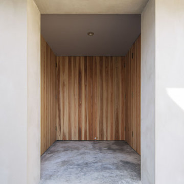 玄関廻りは同幅の杉板を張り,目地や枠材などを極力見えないよう設計,またモルタル壁の厚みを広くとることで蔵のような重厚なイメージとした