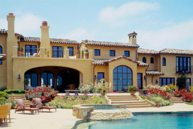 Example of a huge tuscan beige two-story stucco exterior home design in San Diego with a tile roof