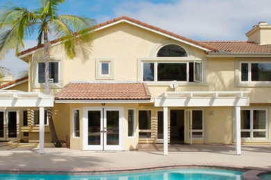 Mid-sized island style yellow two-story stucco exterior home photo in San Diego with a tile roof