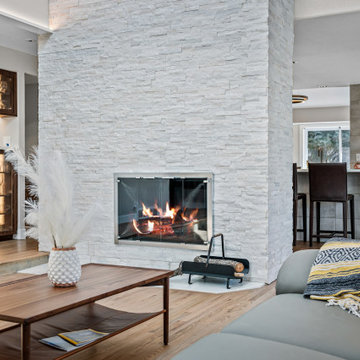 TEXTURED STACKED STONE WRAP A DRAMATIC FIREPLACE ON FOURR SIDES