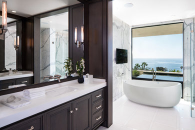 Freestanding bathtub - large contemporary master white tile, gray tile and marble tile white floor freestanding bathtub idea in Phoenix with recessed-panel cabinets, dark wood cabinets, an undermount sink, brown walls and quartzite countertops