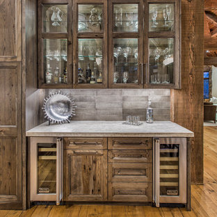 デンバーの中サイズのラスティックスタイルのおしゃれなウェットバー (ガラス扉のキャビネット、ヴィンテージ仕上げキャビネット、コンクリートカウンター、グレーのキッチンパネル、セメントタイルのキッチンパネル、淡色無垢フローリング、シンクなし、茶色い床) の写真