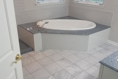 Inspiration for a large timeless master gray floor corner bathtub remodel in Philadelphia with white cabinets, white walls, an undermount sink and raised-panel cabinets
