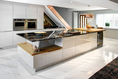 Inspiration for a mid-sized contemporary eat-in kitchen in Other with flat-panel cabinets, with island, white floor, white cabinets, granite benchtops, metallic splashback, mirror splashback, stainless steel appliances and porcelain floors.